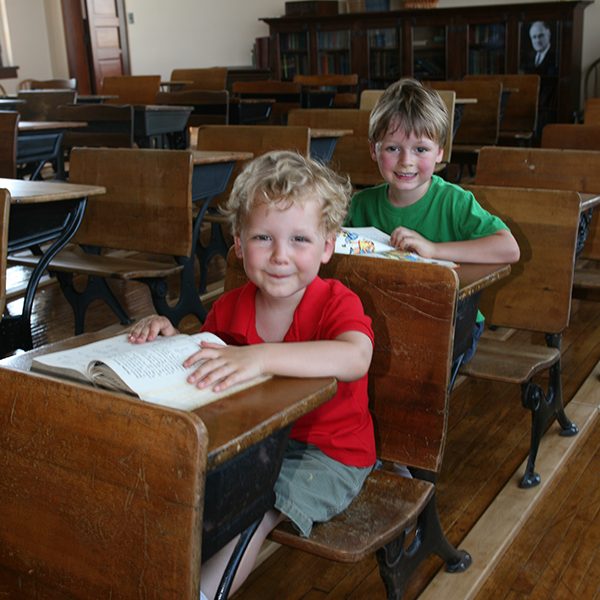 Kids reading books in a Reed School classroom smile towards the camera